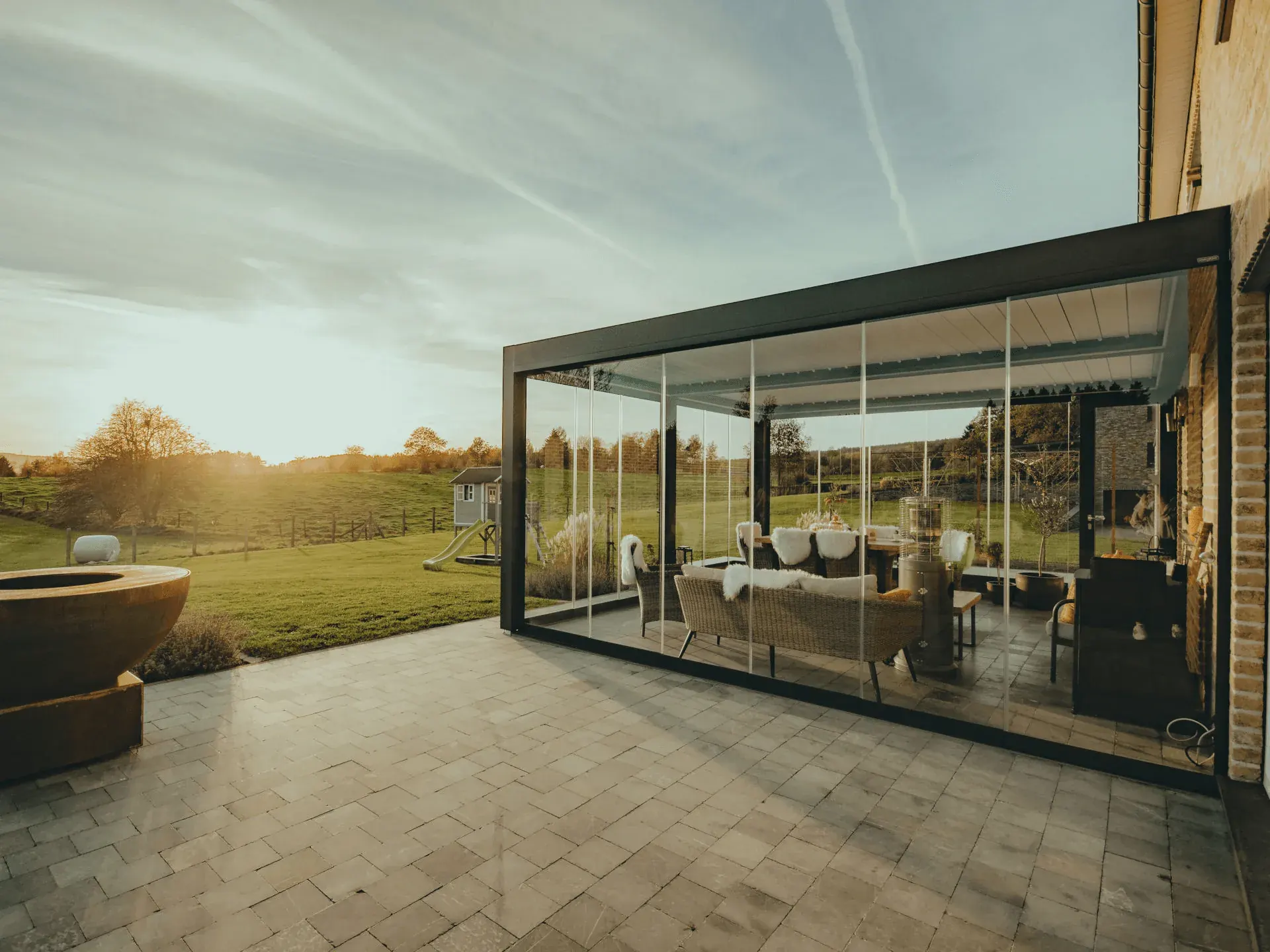 Pérgola bioclimática acristalada instalada por BeIn Solucions, con la terraza al atardecer